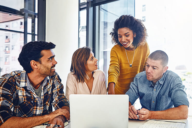 Colleagues huddled around a laptop as they collaborate