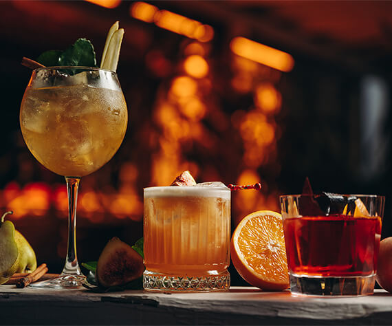 Three cocktails in a glowing bar background.